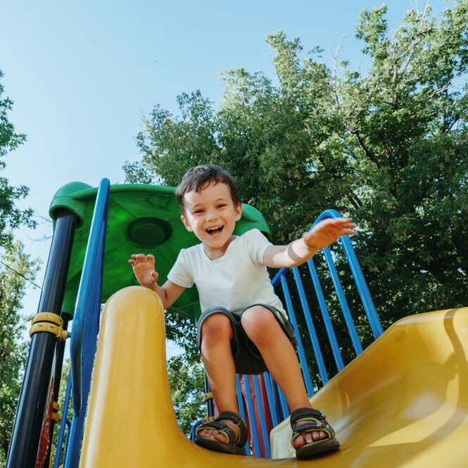 child playing on playground going down slide 